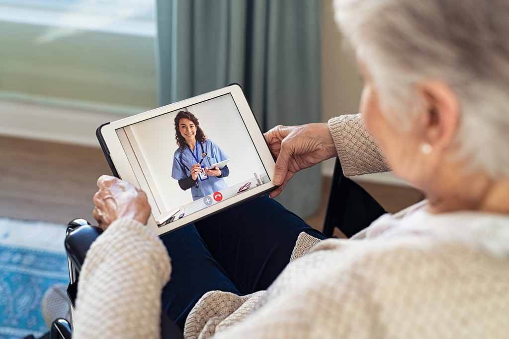 Patienten spricht mit Pflegerin über Tablet